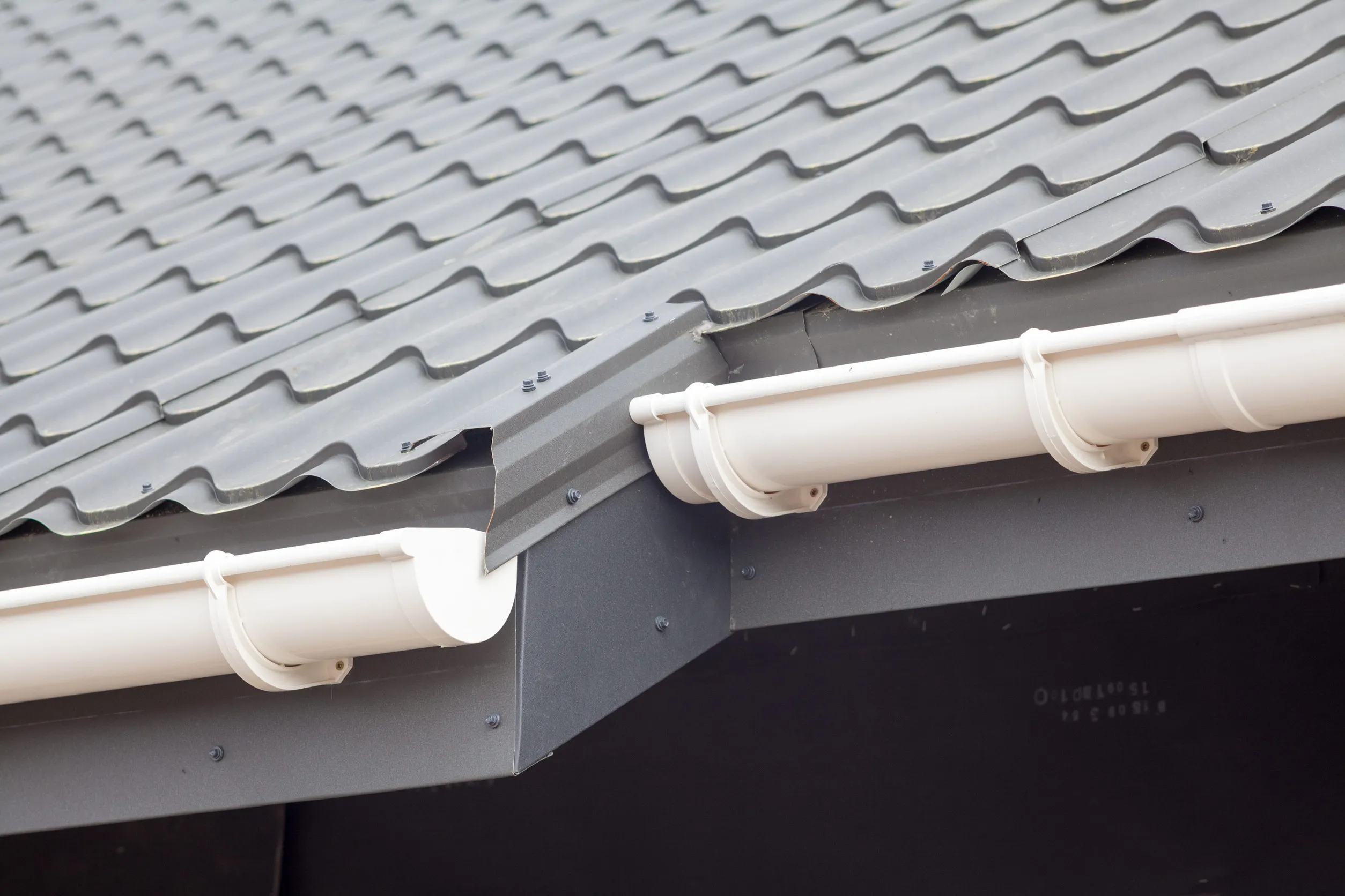 New gray metal tile roof with white rain gutter